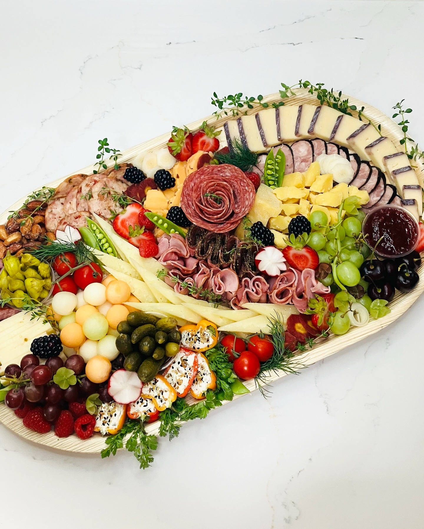 Large grazing platter with ham ruffles, salami rose, sliced cheeses, melon balls, and stuffed mini peppers