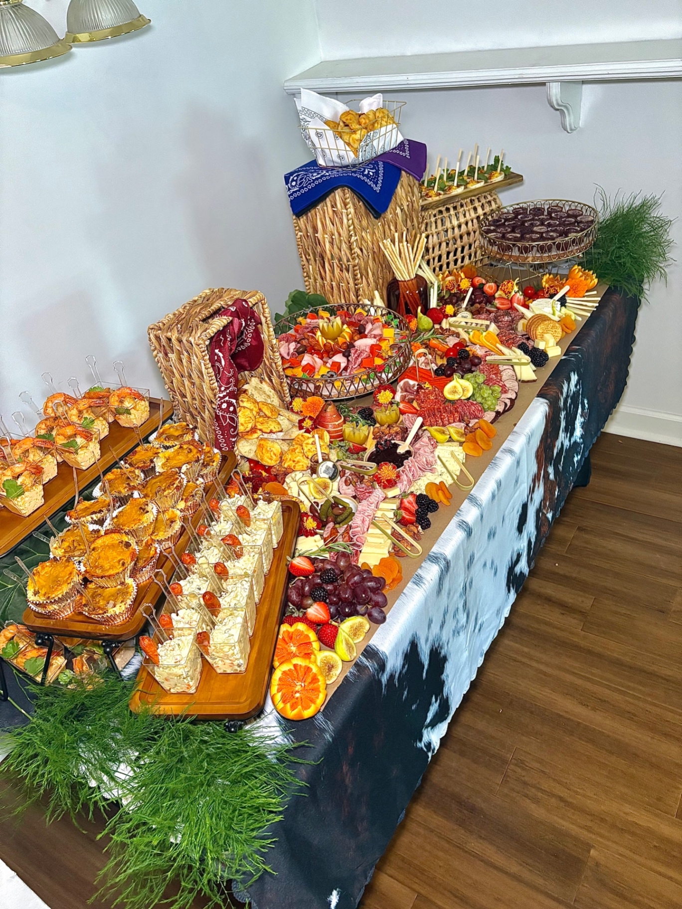Western-themed grazing table with charcuterie boards, shrimp cups, and baked appetizers