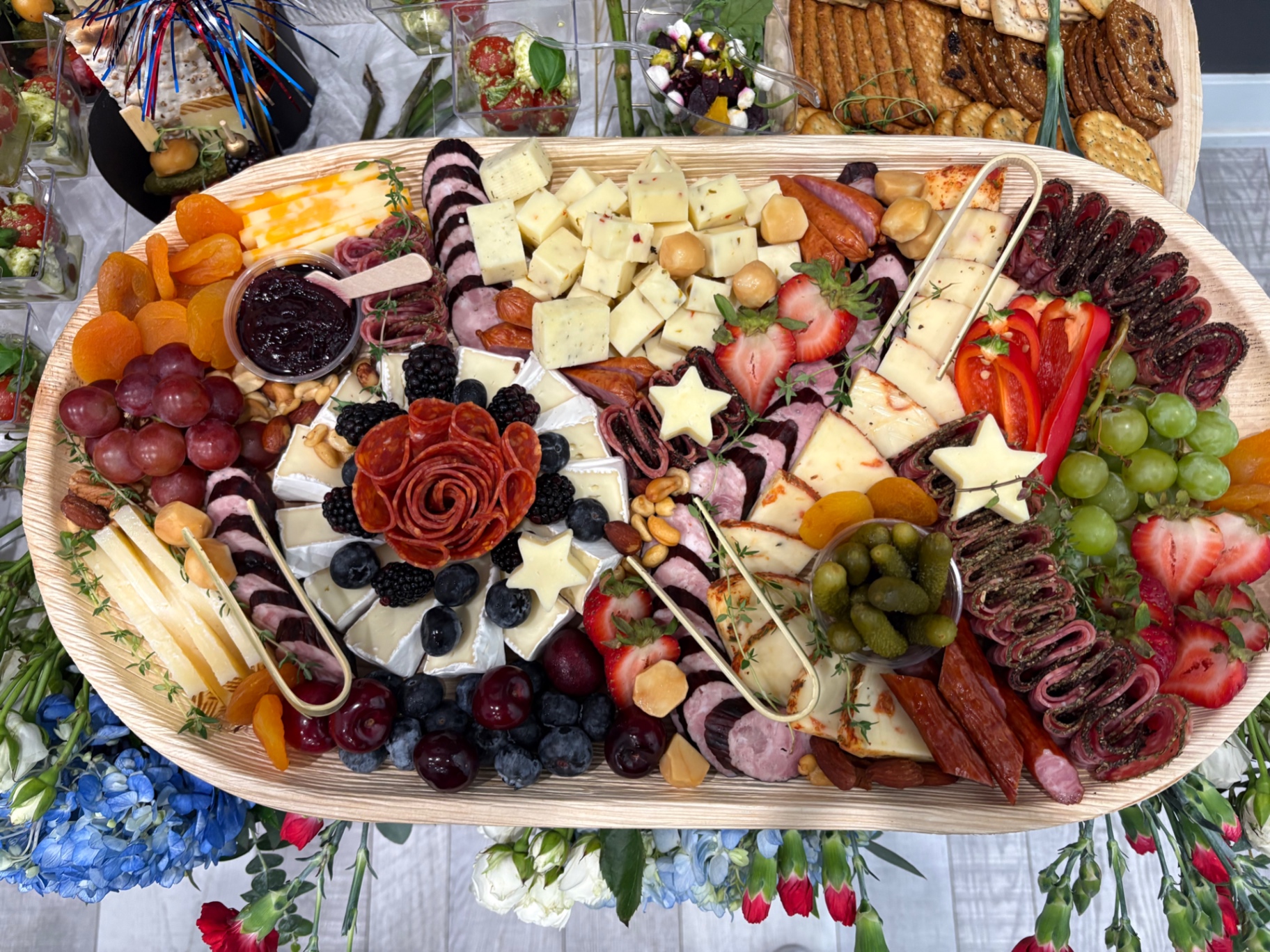 Oval charcuterie board with a pepperoni rose, brie, star cheese cutouts, berries, and cornichons