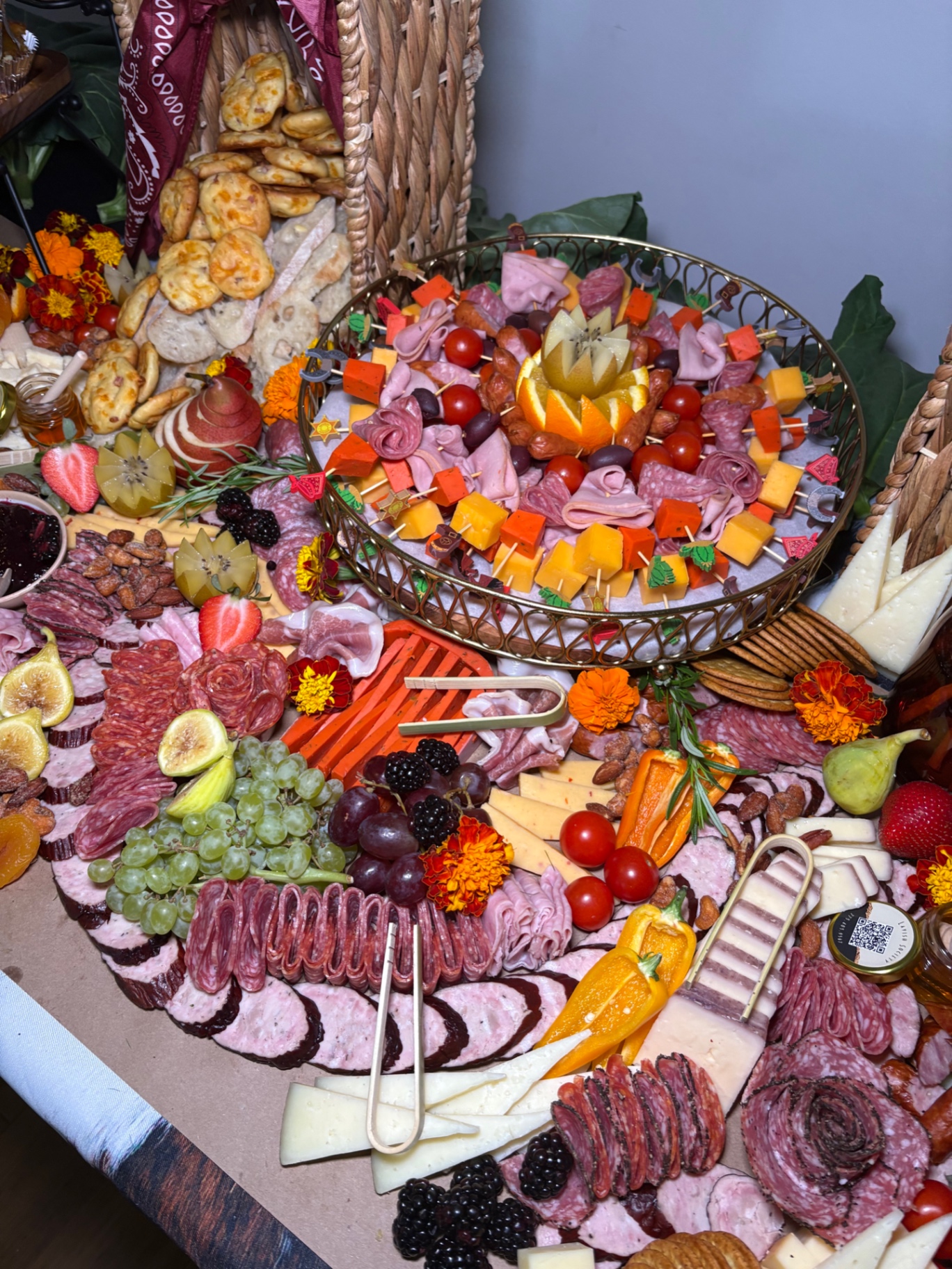 Fall charcuterie spread with appetizer skewers on a gold tray, marigolds, figs, cheeses, and cured meats
