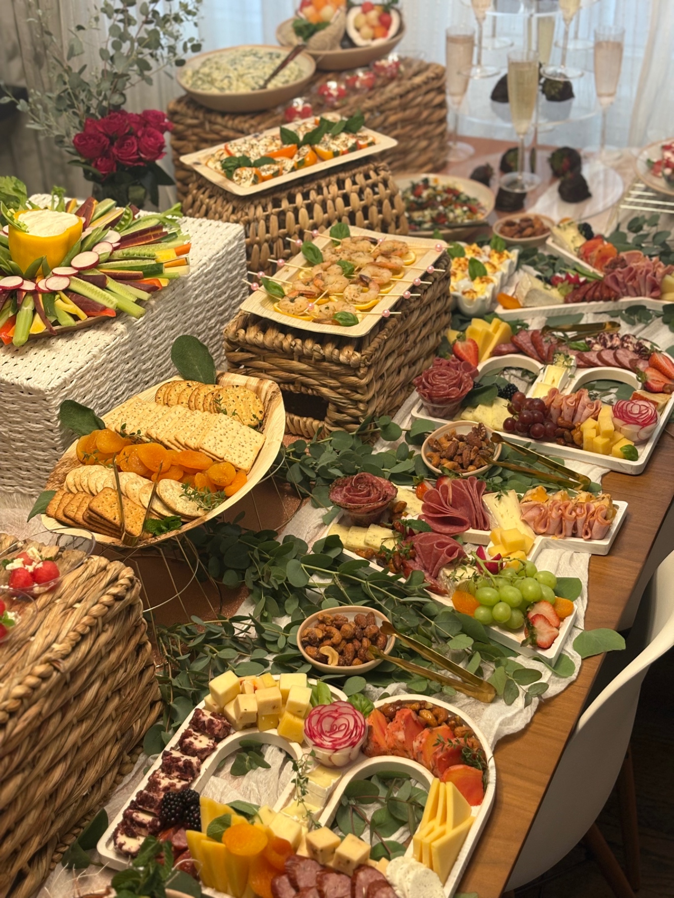 Baby shower grazing table with shrimp skewers, a crudite dip flower, deviled eggs, and heart-shaped charcuterie trays