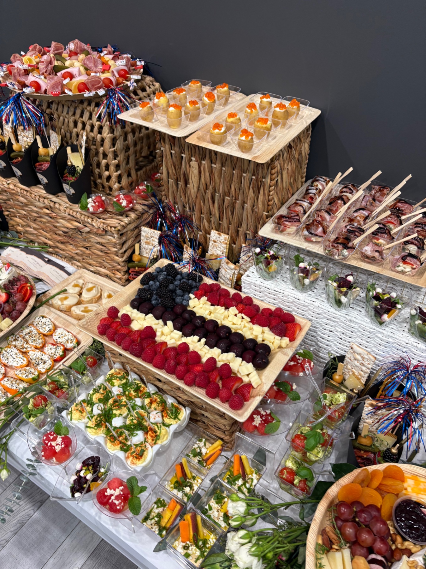 Corporate event spread with a berry and cheese flag tray, deviled eggs, salad cups, and appetizer skewers
