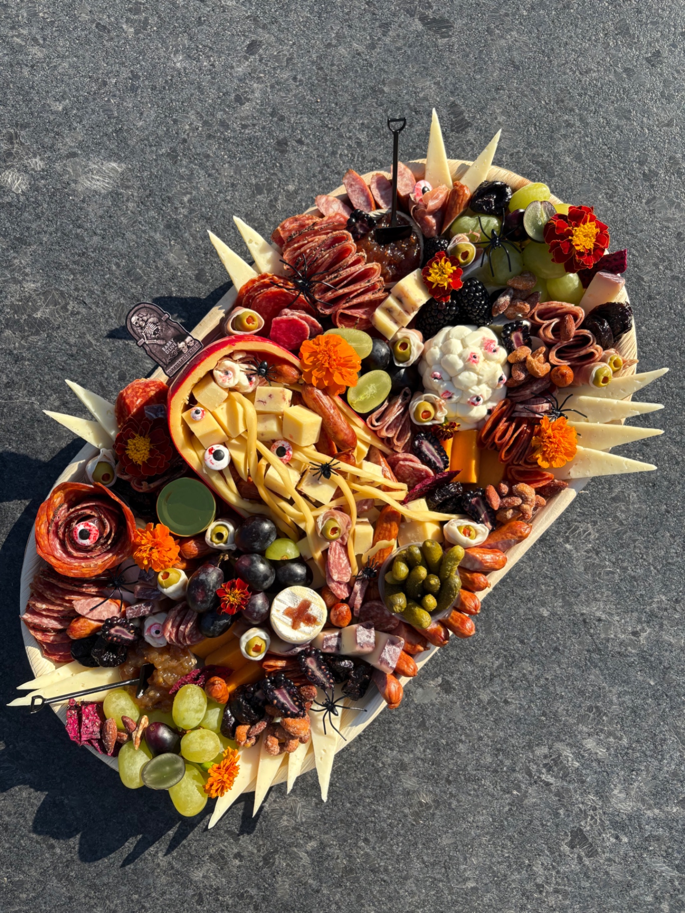 Halloween charcuterie board with candy eyeballs, spider decorations, and a cauliflower brain centerpiece