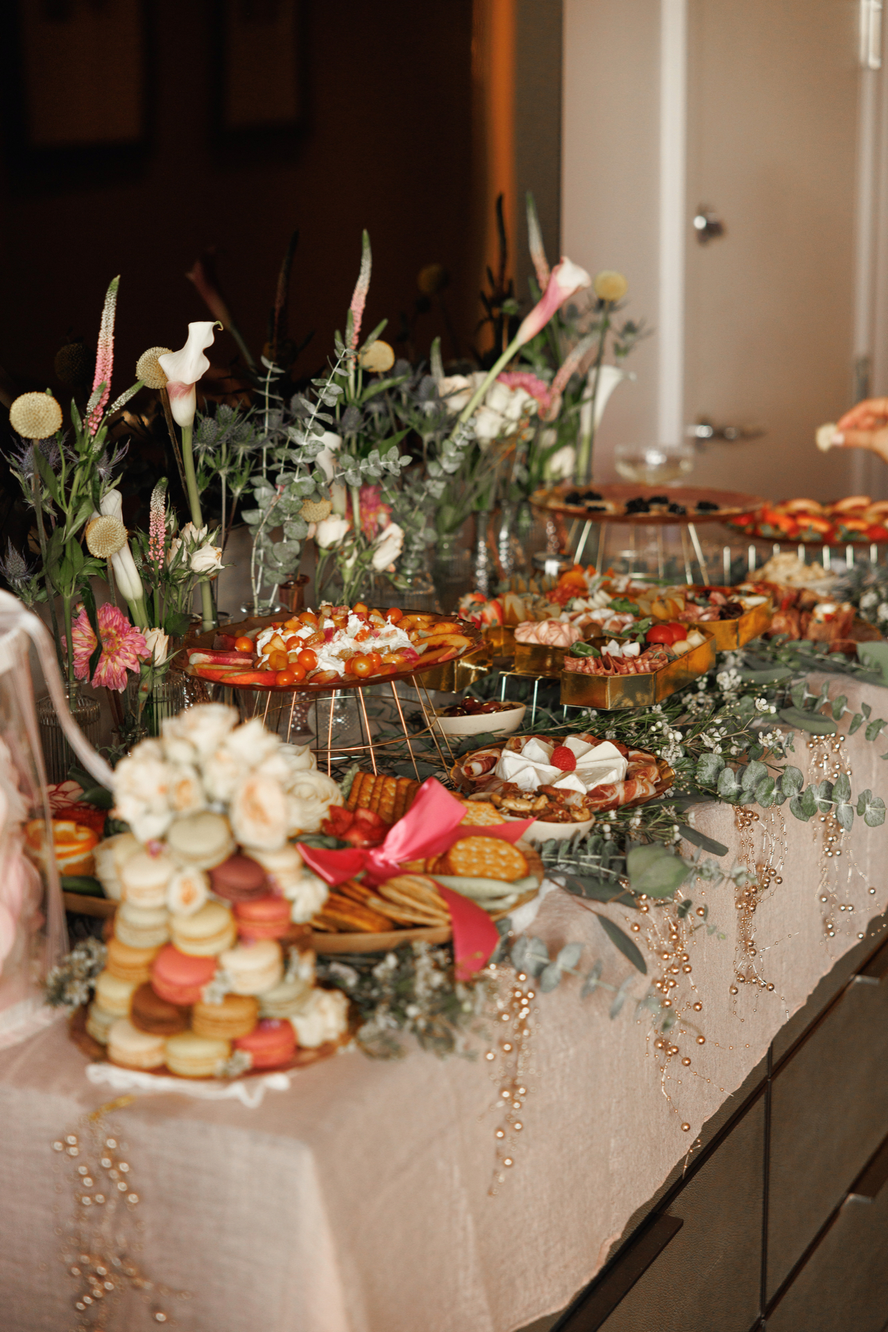 Bachelorette celebration table with a macaron tower, charcuterie letter trays, brie with raspberry, and fresh flowers