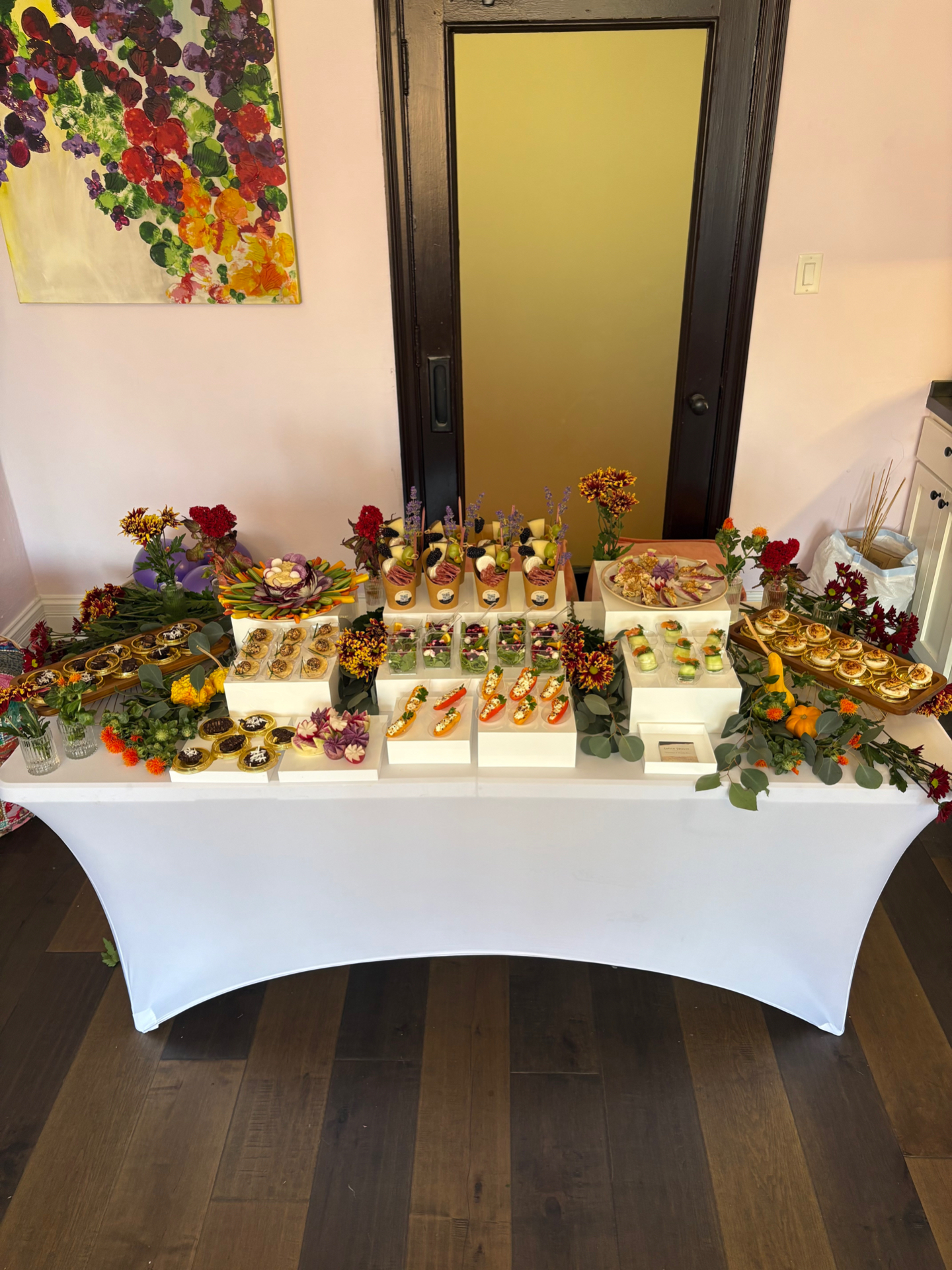 Baby shower appetizer display with charcuterie cones, stuffed mini peppers, salad cups, and deviled eggs among fall flowers